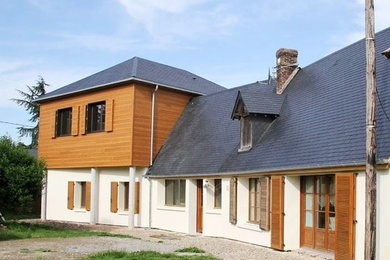 Exemple d'une grande façade de maison beige tendance à deux étages et plus avec un revêtement mixte, un toit à quatre pans et un toit en tuile.