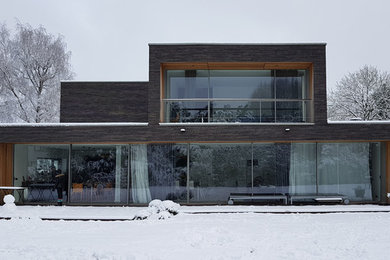 Aménagement d'une grande façade de maison marron contemporaine en brique à deux étages et plus avec un toit plat.