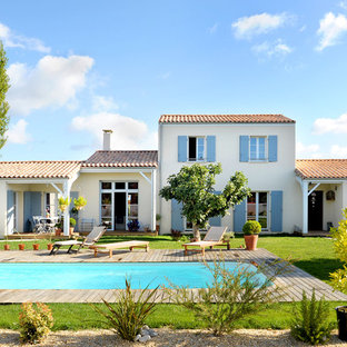 Cette photo montre une grand façade de maison beige méditerranéenne à un étage avec un toit à deux pans.