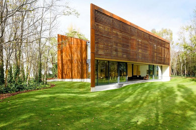 Cette image montre une grande façade de maison design en bois à un étage avec un toit plat.