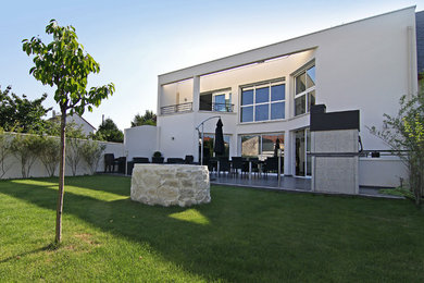Diseño de fachada blanca actual de dos plantas con revestimiento de hormigón y tejado plano