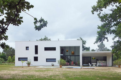 Modelo de fachada blanca minimalista de tamaño medio de dos plantas con tejado plano