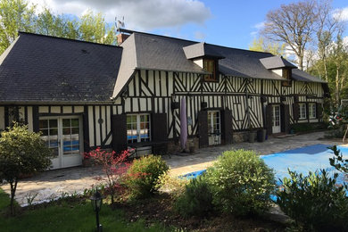 Idée de décoration pour une grande façade de maison beige champêtre en bois à deux étages et plus avec un toit à quatre pans et un toit en tuile.