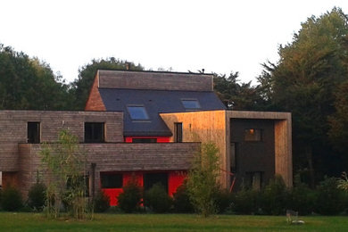 Cette image montre une grande façade de maison marron à un étage avec un revêtement mixte, un toit plat et un toit en shingle.