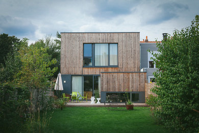 Cette photo montre une façade de maison marron tendance en bois à un étage avec un toit plat.