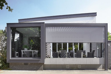 Idée de décoration pour une façade de petite villa grise minimaliste en brique de taille moyenne et à un étage avec un toit en appentis.
