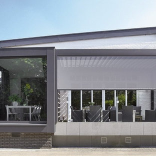 Idée de décoration pour une façade de maison grise minimaliste de taille moyenne et à un étage avec un toit en appentis.