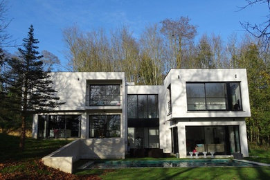 Idée de décoration pour une grande façade de maison blanche minimaliste en béton à un étage avec un toit plat.