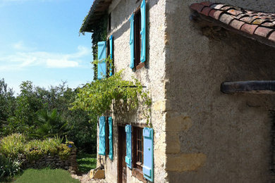 Exemple d'une façade de maison nature en pierre de taille moyenne et à un étage avec un toit à quatre pans.