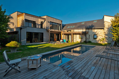 Inspiration pour une grande façade de maison design en bois à un étage avec un toit plat et un toit mixte.