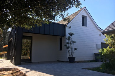 Inspiration pour une petite façade de maison grise design en béton à un étage avec un toit plat.