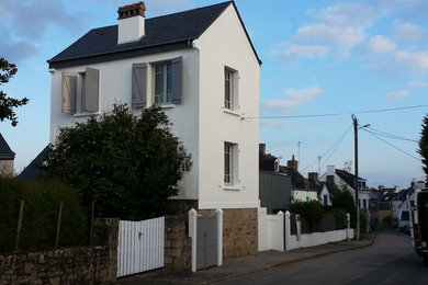 Cette photo montre une façade de maison blanche bord de mer en béton de taille moyenne et à un étage avec un toit à deux pans.