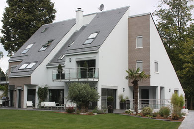 Exemple d'une grande façade de maison blanche tendance à deux étages et plus avec un toit à deux pans, un toit en tuile et un revêtement mixte.