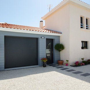 Cette image montre une grand façade de maison multicolore méditerranéenne à un étage avec un toit en tuile, un revêtement en stuc et un toit à quatre pans.