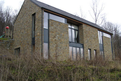 Cette image montre une grande façade de maison beige design en pierre à un étage avec un toit à deux pans.