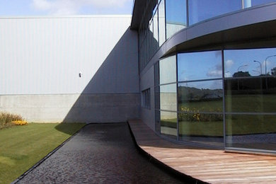 Diseño de fachada gris actual grande de tres plantas con revestimiento de metal y tejado plano