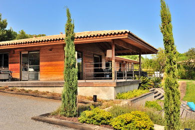 Réalisation d'une très grande façade de maison design en bois de plain-pied avec un toit à quatre pans et un toit en tuile.