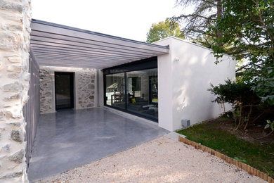 Cette photo montre une façade de maison blanche tendance en pierre de taille moyenne et à un étage avec un toit plat et un toit végétal.