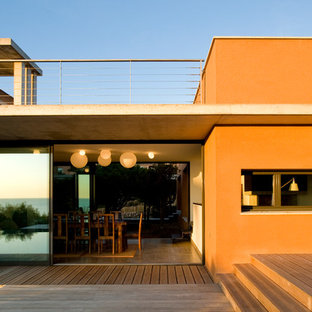 Inspiration pour une façade de maison orange méditerranéenne de taille moyenne et à un étage avec un toit plat.