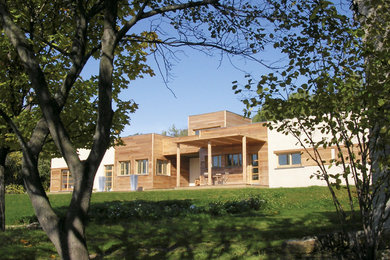 Diseño de fachada de casa beige contemporánea grande de dos plantas con revestimiento de madera, tejado plano y tejado de metal