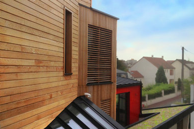 Cette image montre une grande façade de maison marron design en bois à deux étages et plus.