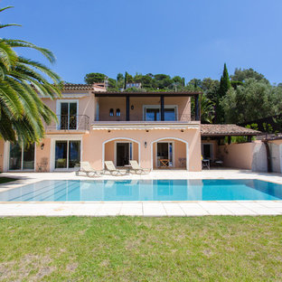 Idée de décoration pour une grand façade de maison beige méditerranéenne à un étage avec un toit à deux pans.