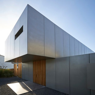 Réalisation d'une grand façade de maison grise design à un étage avec un toit plat.