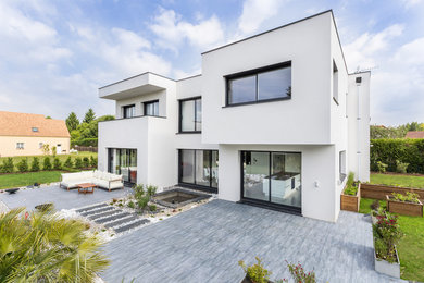 Aménagement d'une grande façade de maison blanche moderne en pierre à un étage avec un toit plat et un toit végétal.