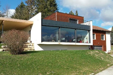 Diseño de fachada de casa marrón grande de dos plantas con revestimientos combinados y tejado plano