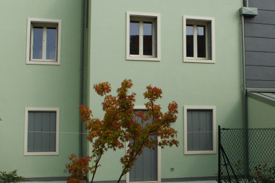 Foto della facciata di una casa bifamiliare verde a tre piani di medie dimensioni con tetto a padiglione e copertura in metallo o lamiera