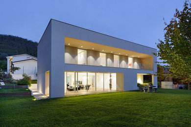 Cette image montre une grande façade de maison blanche minimaliste à un étage avec un toit plat.
