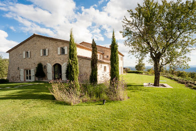 Photo of a farmhouse two floor house exterior in Milan with stone cladding and a pitched roof.