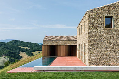 Esempio della villa ampia beige contemporanea a tre piani con rivestimento in pietra, tetto a capanna e copertura in tegole
