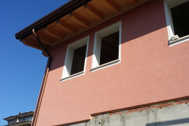 Foto della villa piccola multicolore country a un piano con rivestimento in stucco, tetto a capanna e copertura in tegole