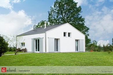 Immagine della villa piccola bianca contemporanea a due piani con rivestimento in legno, tetto a capanna e copertura in tegole