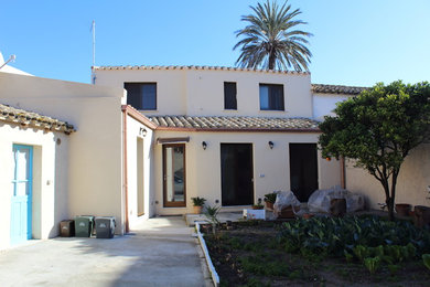 Diseño de fachada de casa beige mediterránea de tamaño medio de dos plantas con tejado a dos aguas y tejado de teja de barro