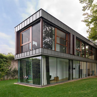 Foto della villa grigia contemporanea a due piani con rivestimento in vetro e tetto piano