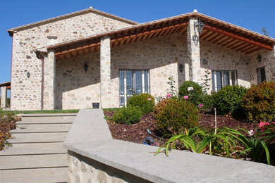 Foto della villa grande country a due piani con rivestimento in pietra, copertura in tegole e tetto a capanna