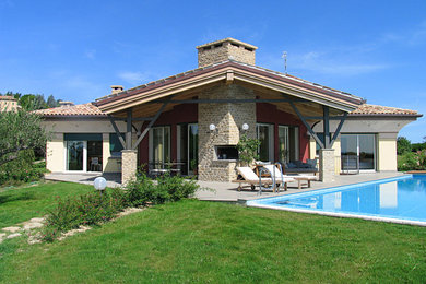 Immagine della villa grande rustica a due piani con rivestimento in pietra, copertura in tegole e falda a timpano