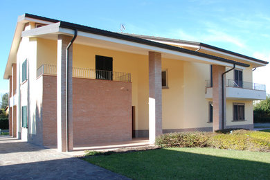 Ejemplo de fachada beige de estilo de casa de campo grande de dos plantas con revestimiento de ladrillo y tejado a cuatro aguas