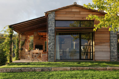 Immagine della micro casa piccola marrone country a un piano con rivestimento in legno, tetto a capanna e copertura in tegole