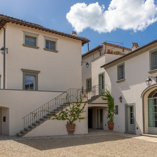 Foto della facciata di una casa grande beige classica a tre piani con tetto a padiglione e copertura in tegole