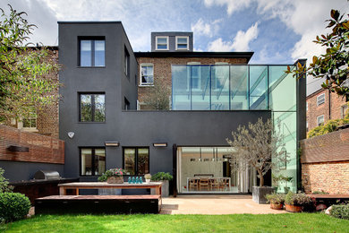 Immagine della facciata di una casa nera contemporanea a tre piani con rivestimento in vetro