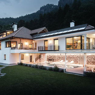 Immagine della facciata di una casa unifamiliare bianca contemporanea a due piani con rivestimenti misti, tetto a padiglione e copertura in tegole
