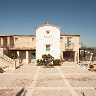 Idee per la facciata di una casa unifamiliare arancione mediterranea a due piani con rivestimento in mattoni, tetto a capanna e copertura in tegole
