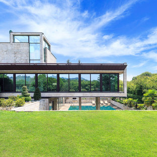 Idee per la villa grigia moderna a tre piani con rivestimento in pietra e tetto piano