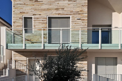 Immagine della facciata di una casa bifamiliare contemporanea a due piani di medie dimensioni con rivestimento in pietra, tetto a capanna e copertura in tegole