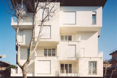 Immagine della facciata di una casa bianca contemporanea a tre piani con rivestimento in adobe e tetto piano
