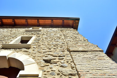 Foto della facciata di una casa bifamiliare mediterranea a tre piani con rivestimento in pietra, tetto a capanna e copertura mista