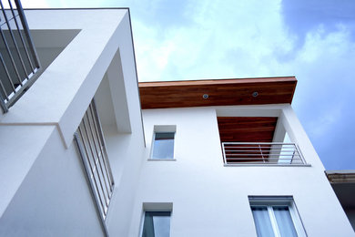 Foto della facciata di una casa bianca contemporanea a tre piani con copertura in metallo o lamiera